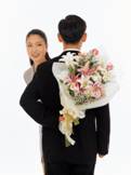 man holding bouquet behind back and surprised woman