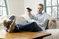 man on couch using tv remote